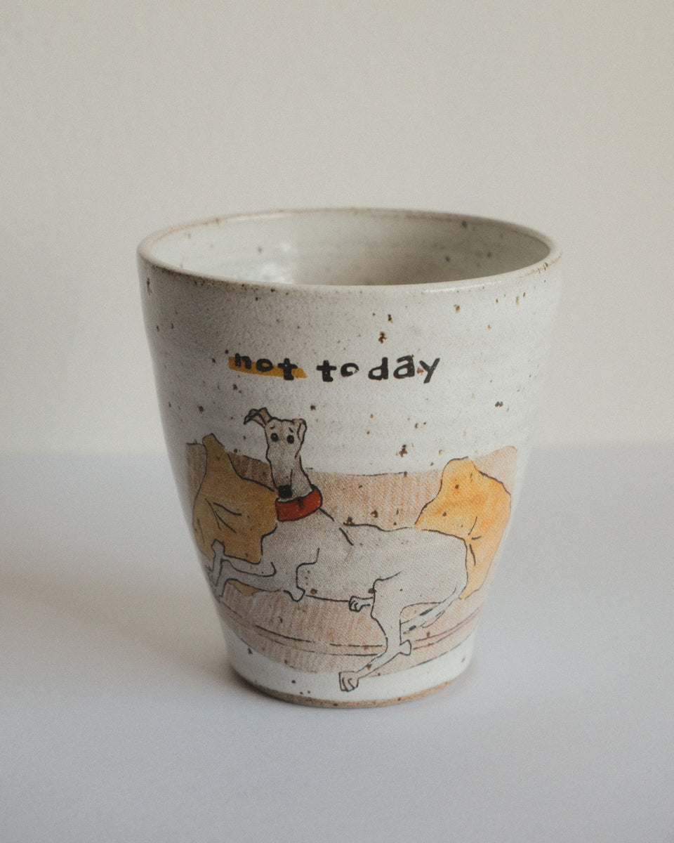 A handmade ceramic cup with a speckled off-white glaze, featuring a hand-drawn illustration of a greyhound dog and the text 'not today' on the front.